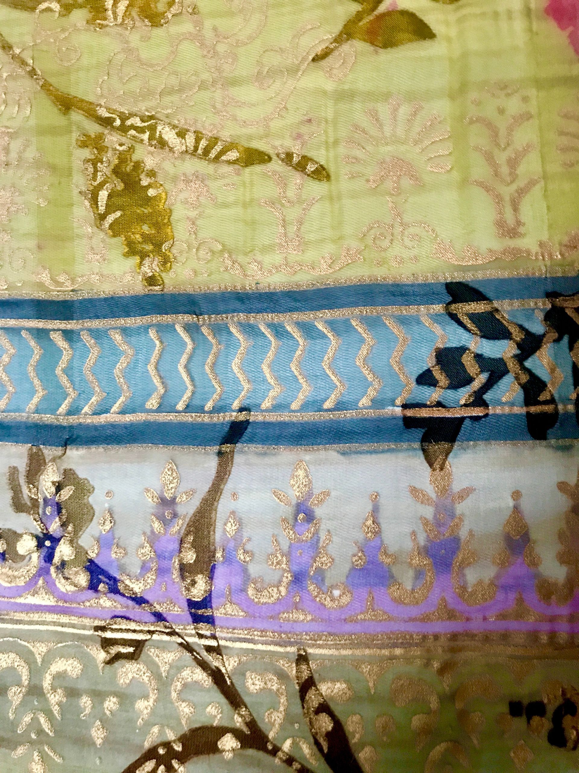 Close-up of fabric with floral and geometric patterns, gold trim, and blue accents.