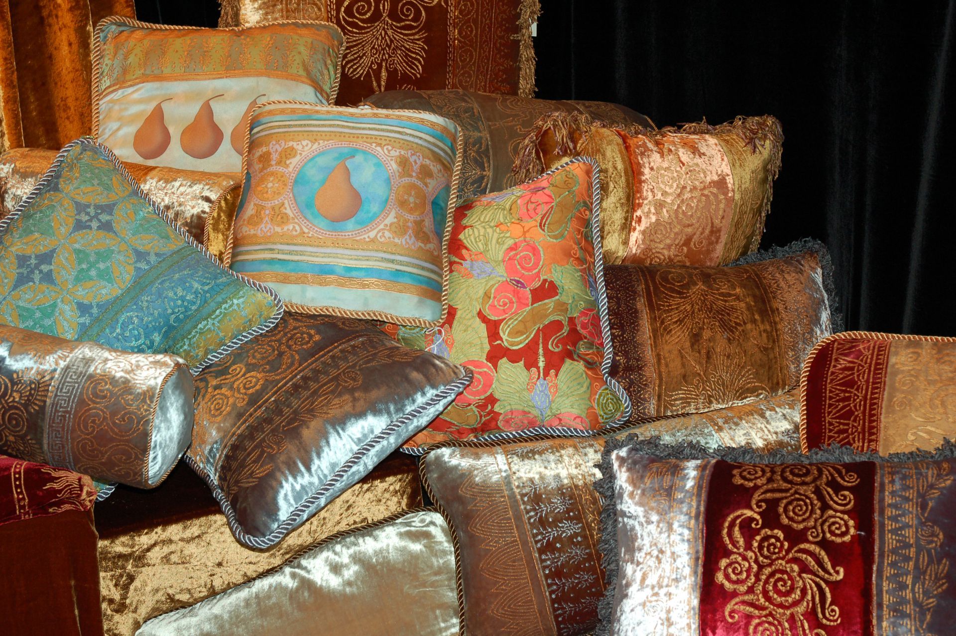 Pile of colorful, ornate decorative pillows with various patterns and textures.