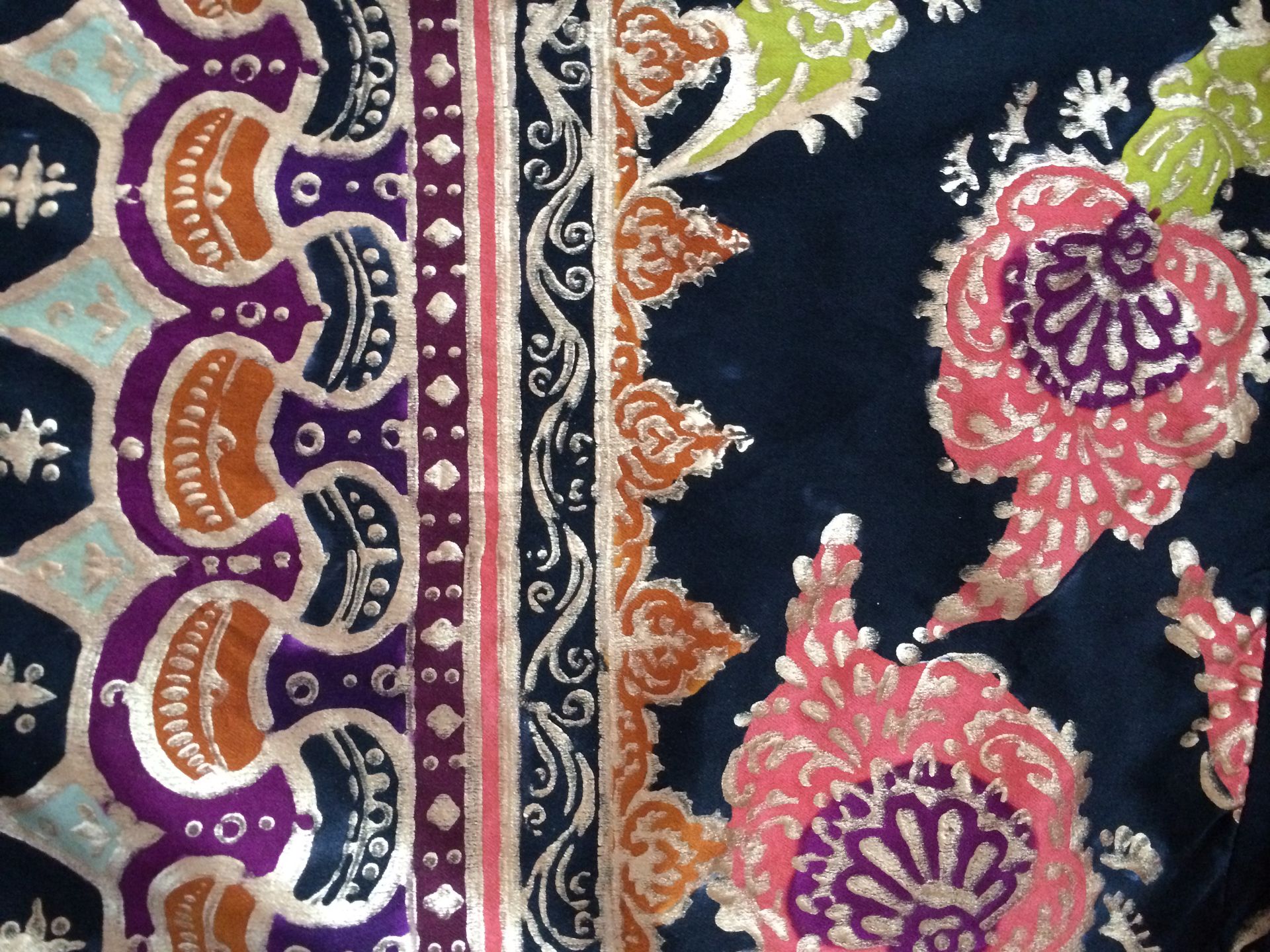 Close-up of printed fabric with floral and geometric patterns in navy, orange, purple, pink, and green.