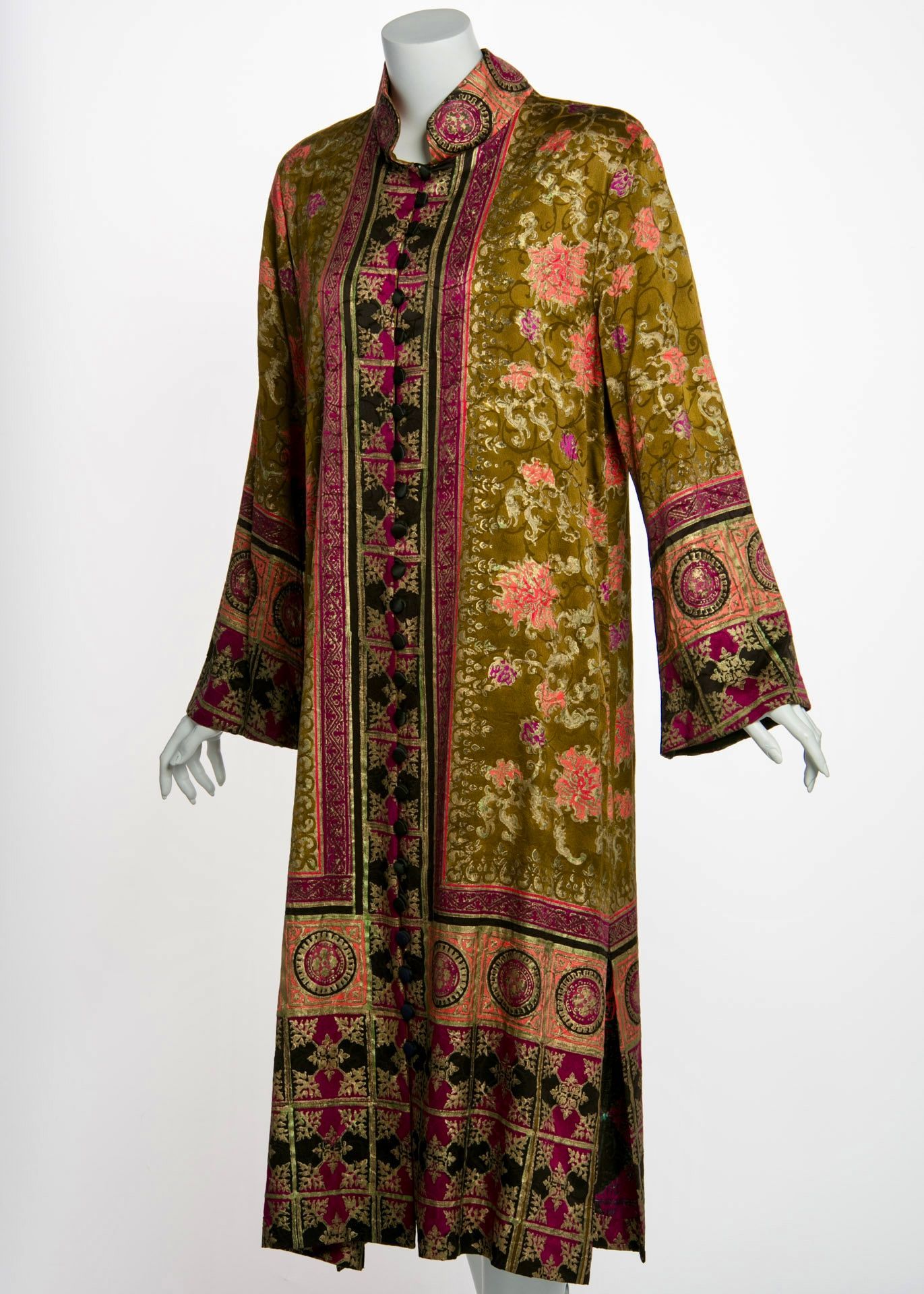 Mannequin wearing a long olive-green dress with floral and geometric patterns in pink and black.