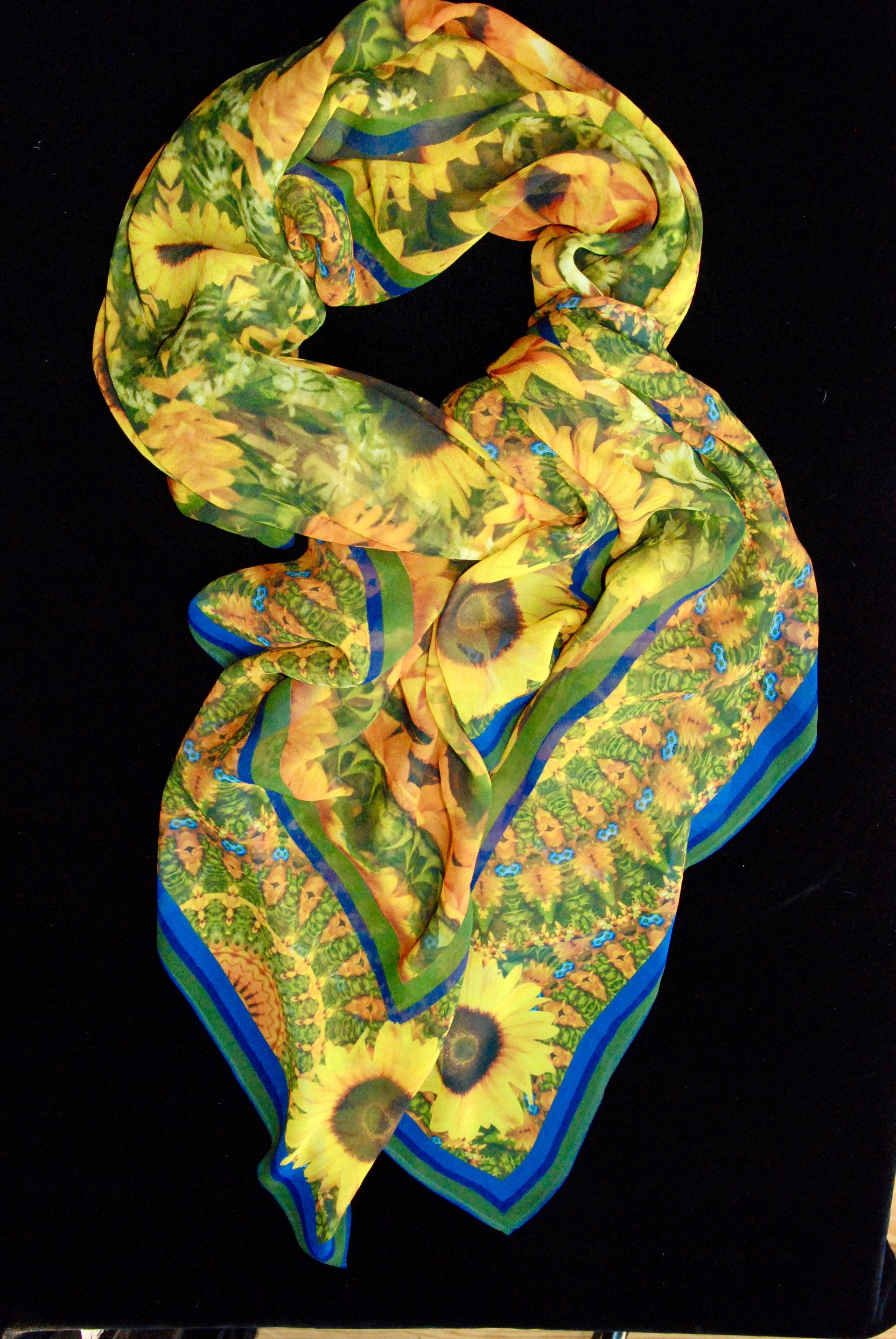 Yellow floral scarf with sunflowers, blue and green borders, draped on black.
