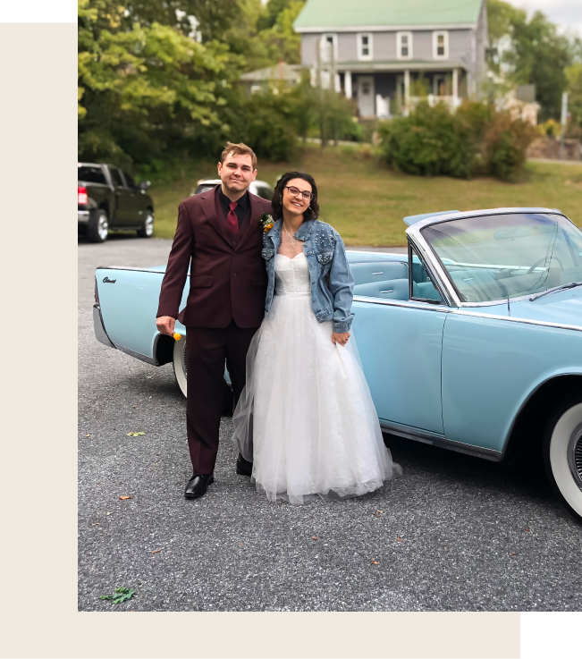 Light blue Lincoln car with a person wearing a cowboy hat in the driver's seat; people in the background.