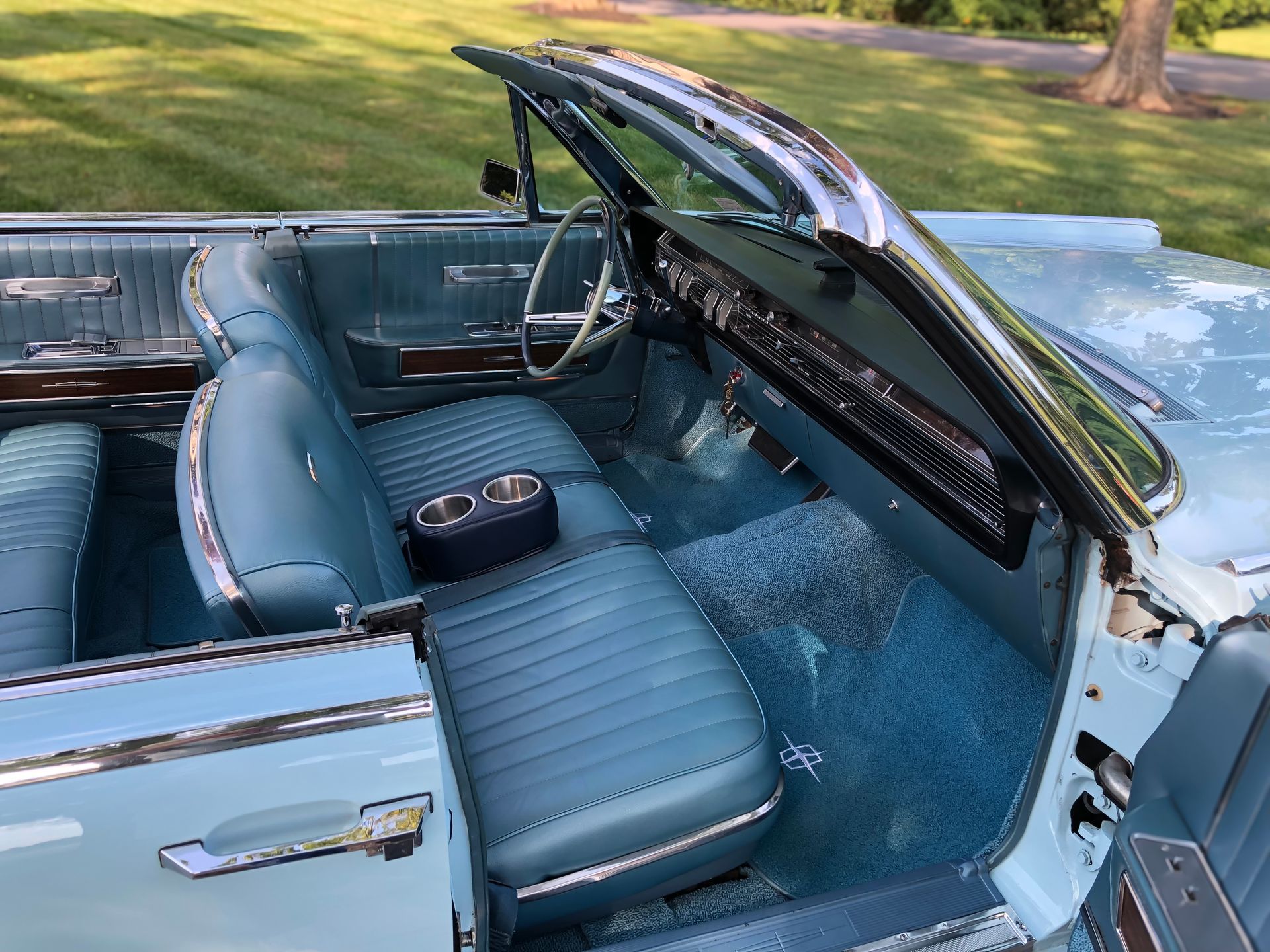 Interior of a light blue convertible car with blue leather seats and dashboard, chrome accents.