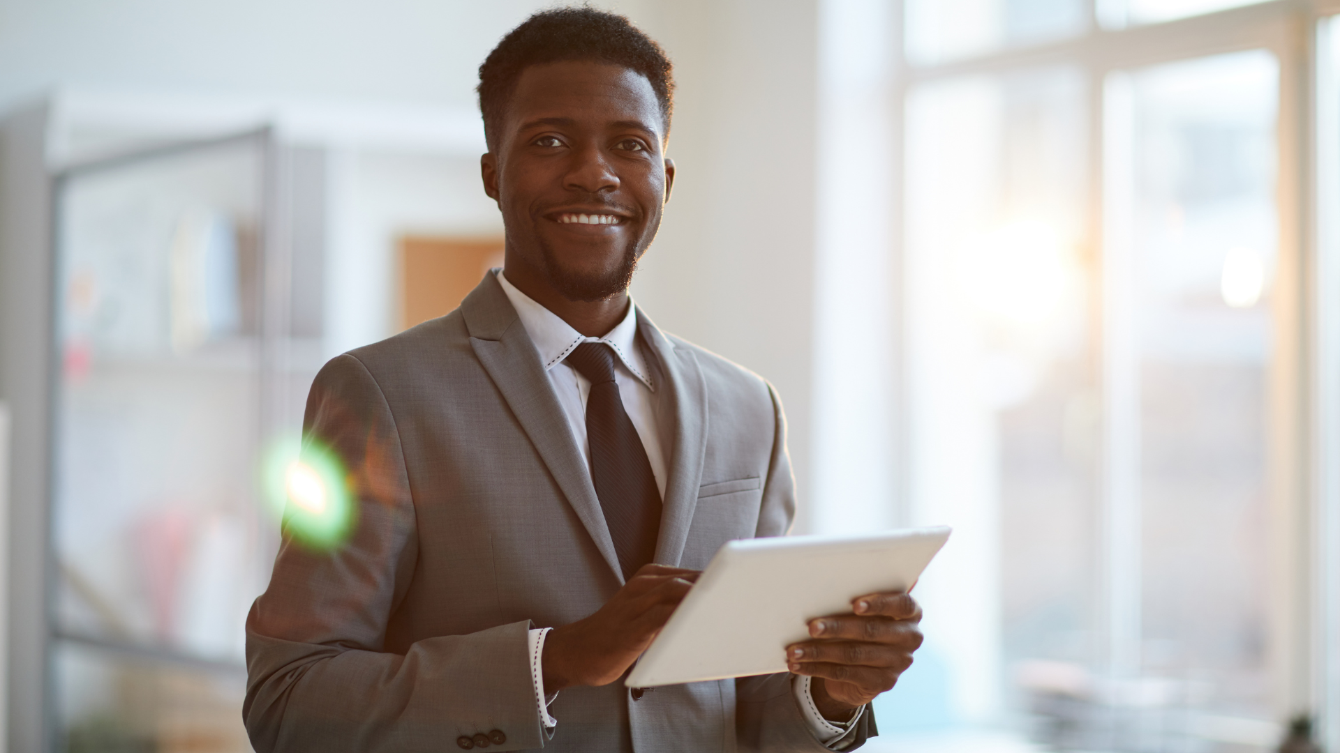 A man in a suit and tie is holding a tablet computer.