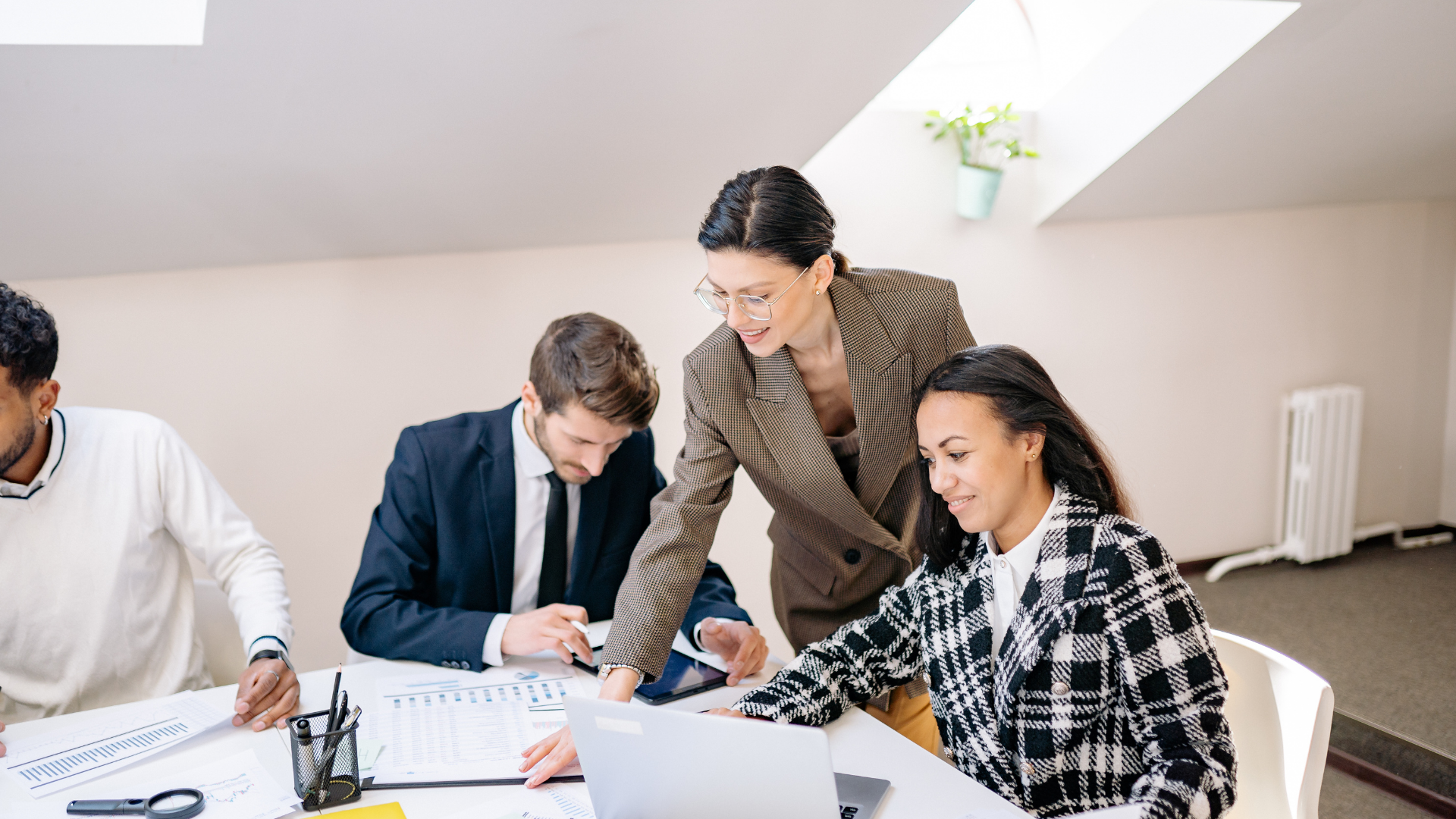 Four business colleagues collaborate around a table, analyzing documents and laptop.