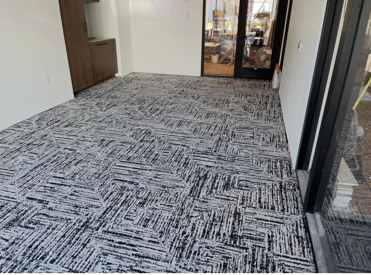 Interior view of a room with patterned carpet and white walls; a doorway is visible.