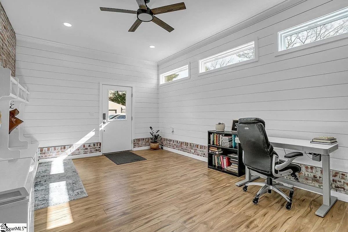 Home office with white walls, wood floors, desk, chair, and small bookcase.