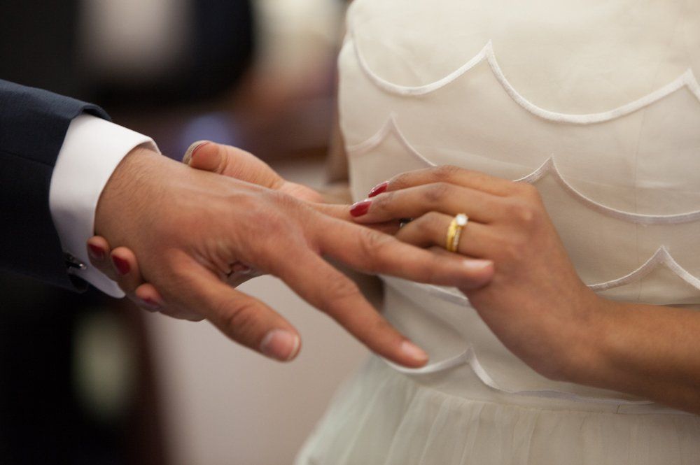 A man is putting a wedding ring on a woman 's finger.