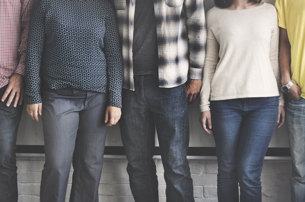 A group of people are standing next to each other in front of a brick wall.