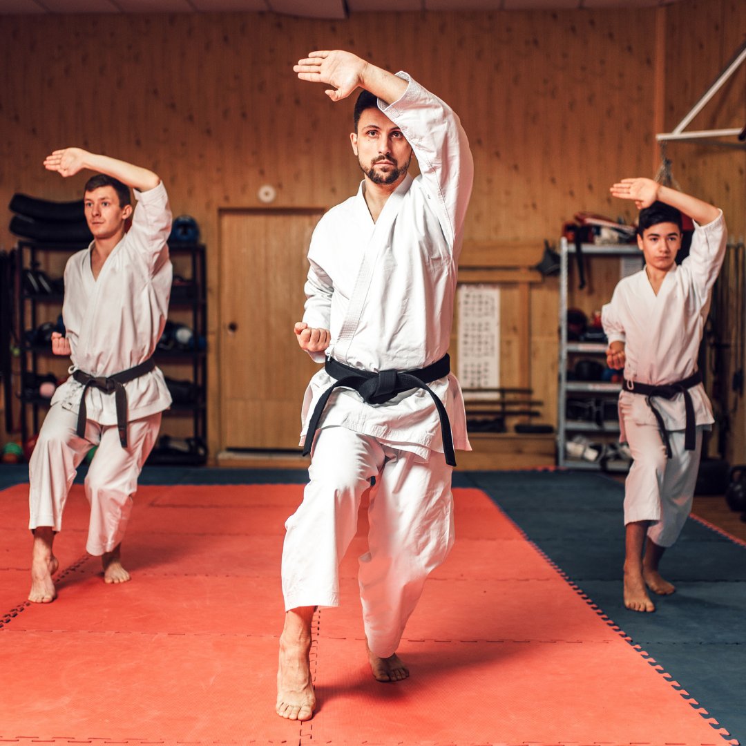 A group of men are practicing karate in a gym.