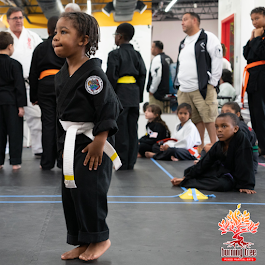 two boys are wrestling with one wearing a black karate uniform with the word jiu-jitsu on it
