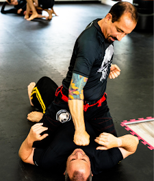 a man in a karate uniform is tying his purple belt .