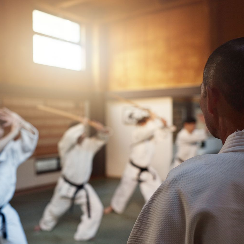 A group of children are practicing karate with a teacher in a gym.