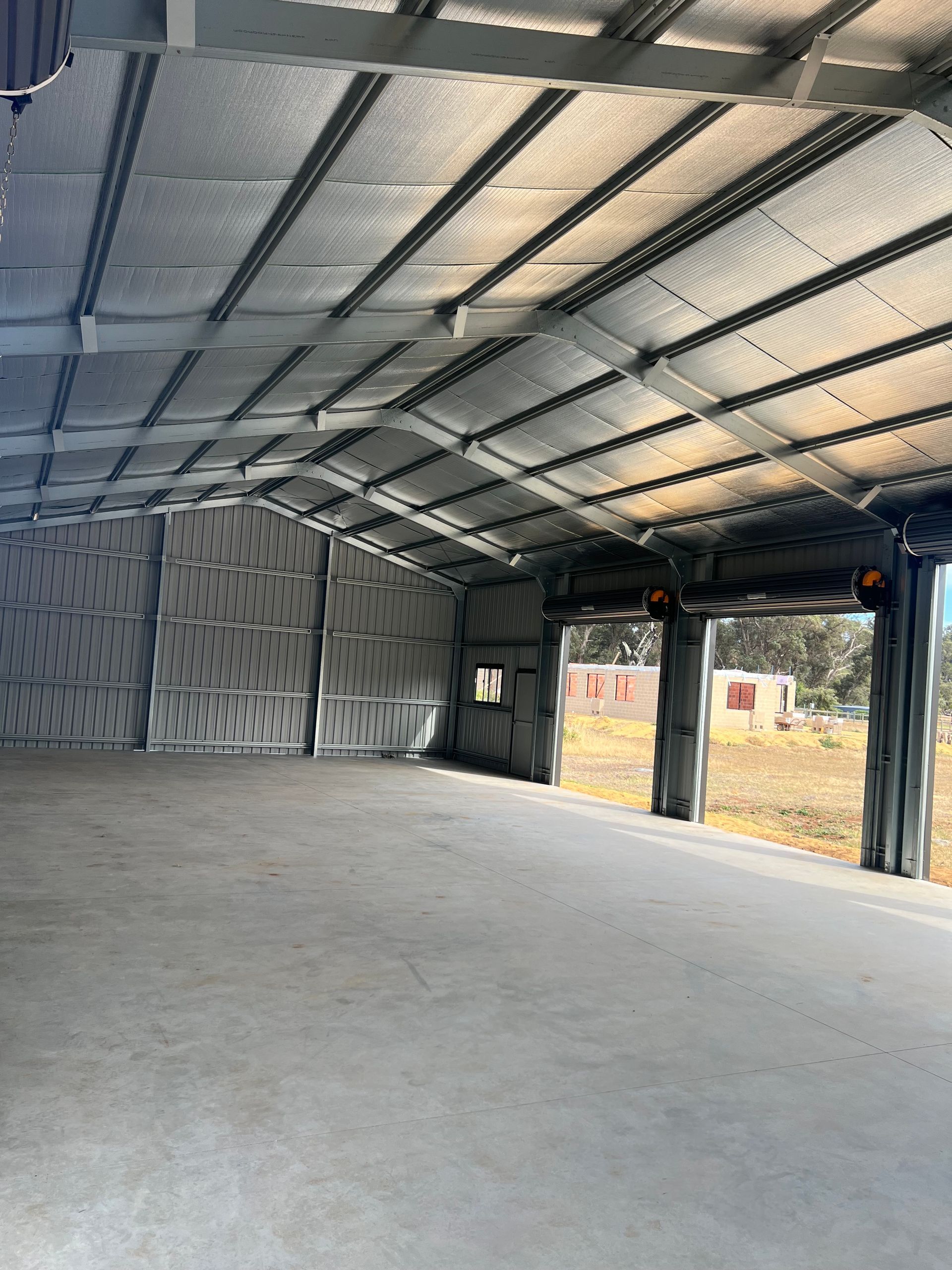 Interior of a large, empty metal building with insulated walls and roof and a concrete floor.