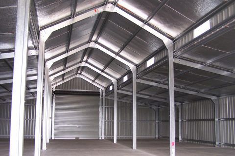 The inside of an empty warehouse with a metal roof