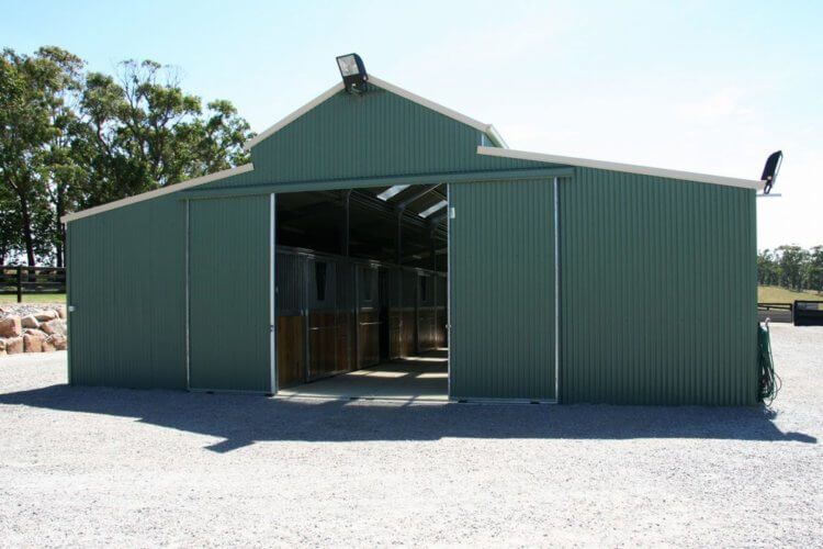 A green barn with a large sliding door