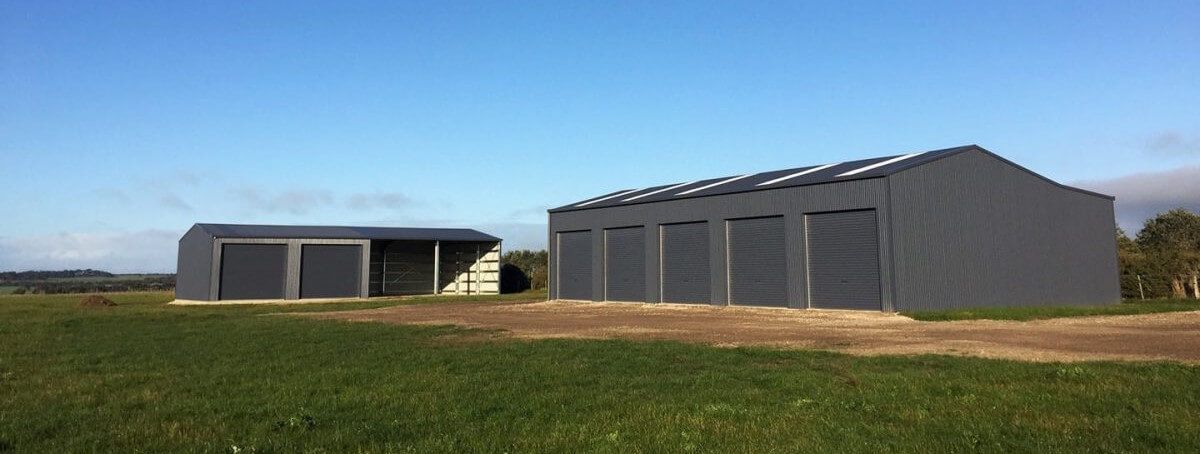 There are two buildings in the middle of a field.