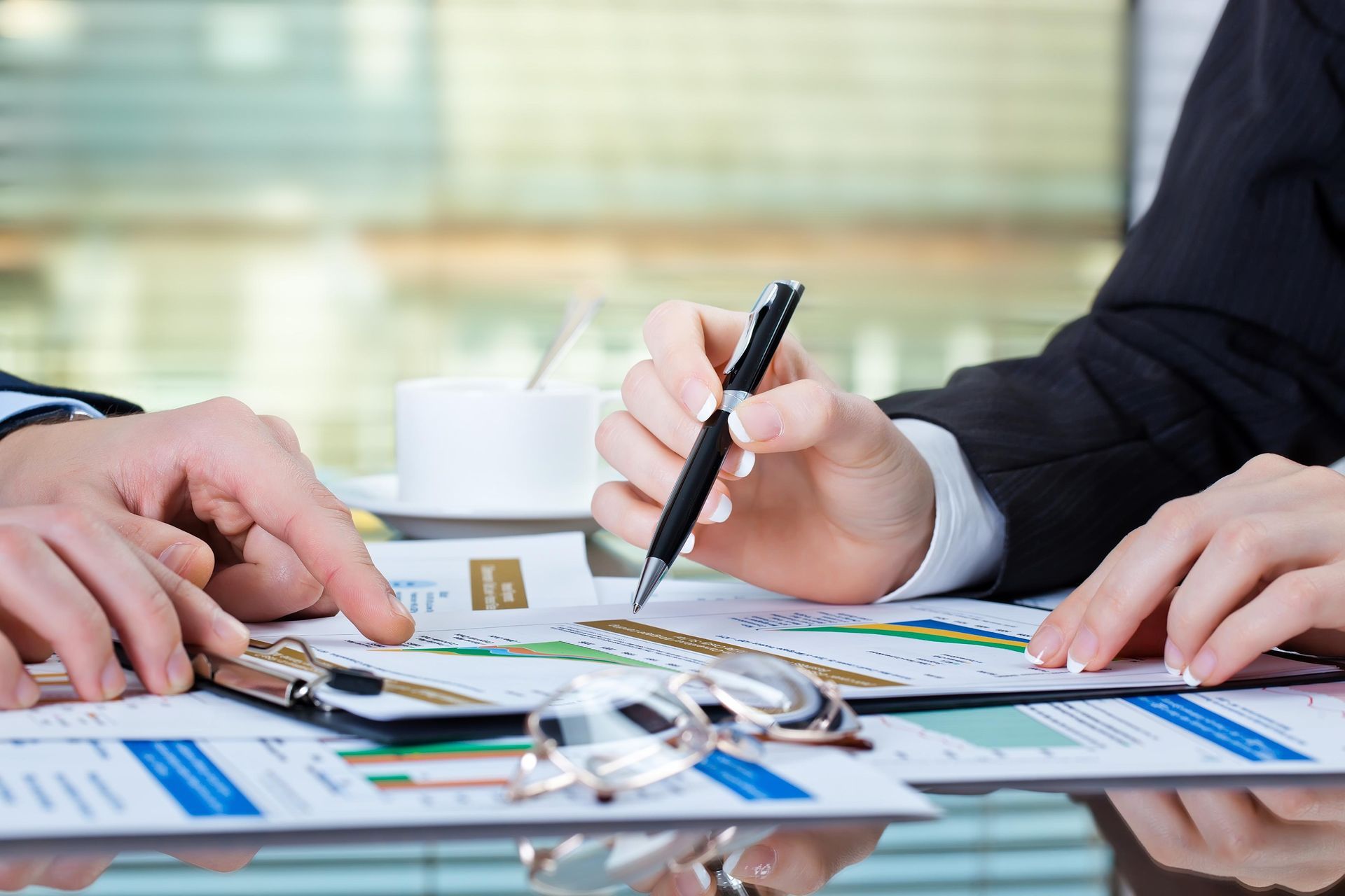 A man and a woman are sitting at a table with papers and a pen.