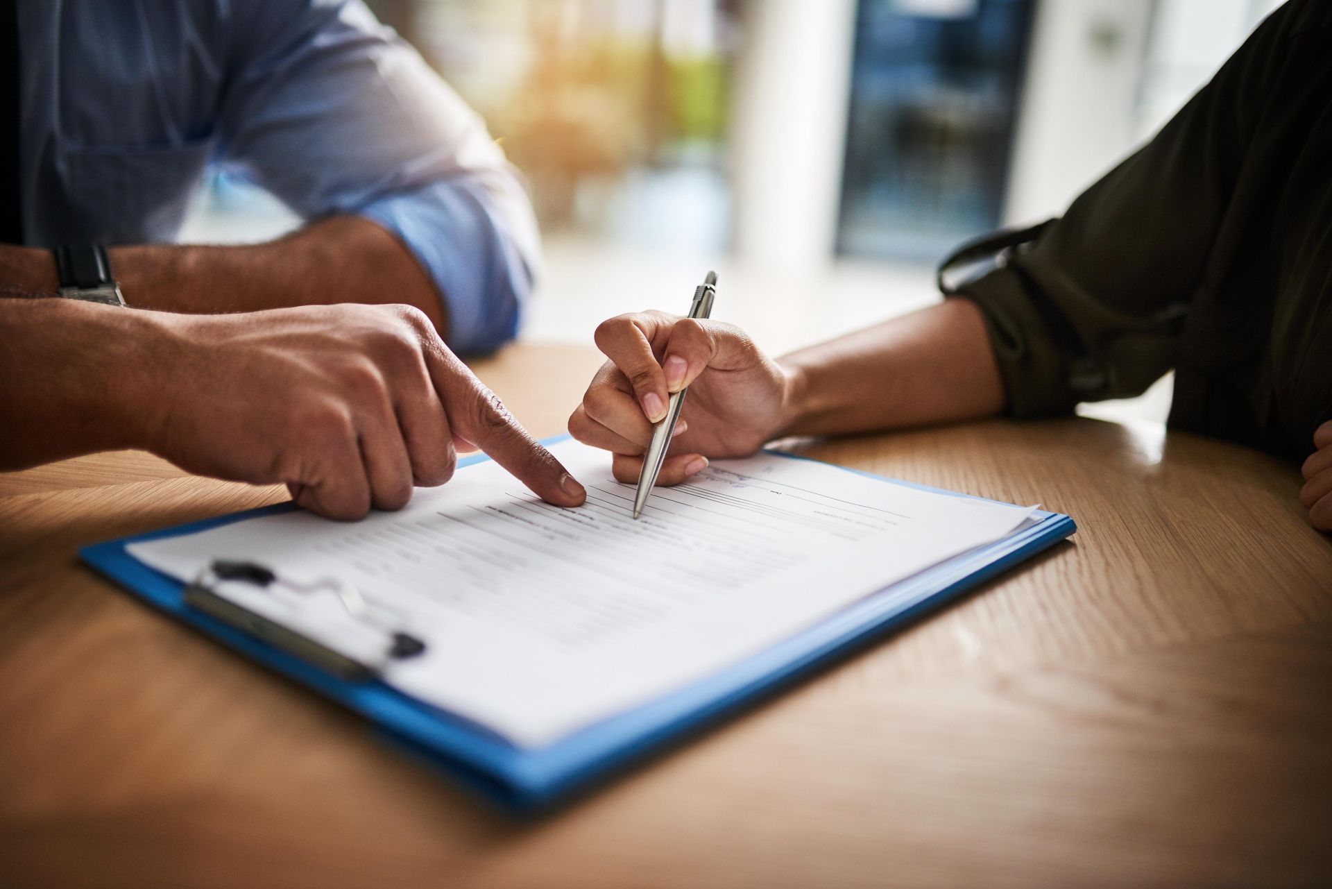 A man and a woman are signing a document on a clipboard.