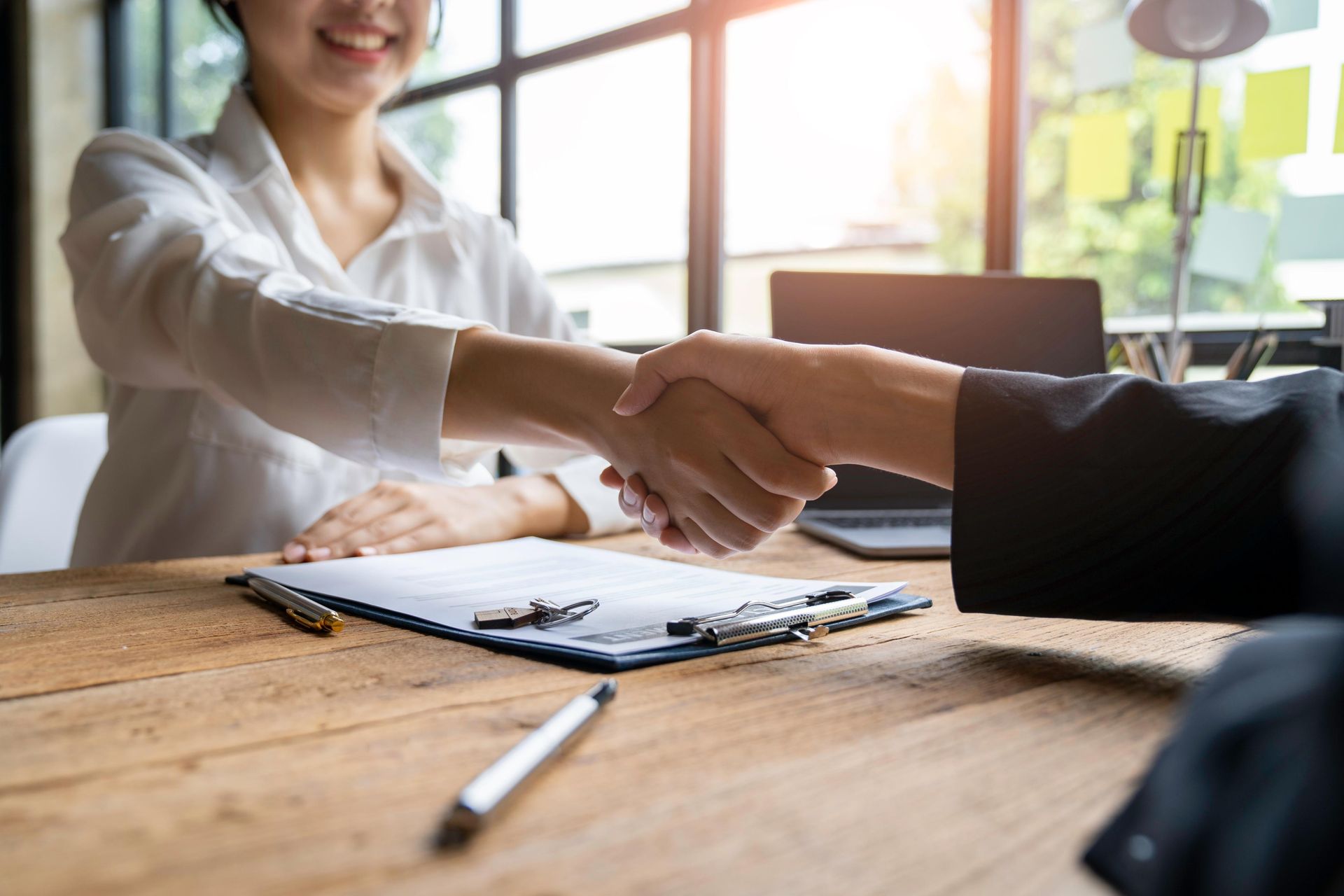 A woman is shaking hands with a man at a table.