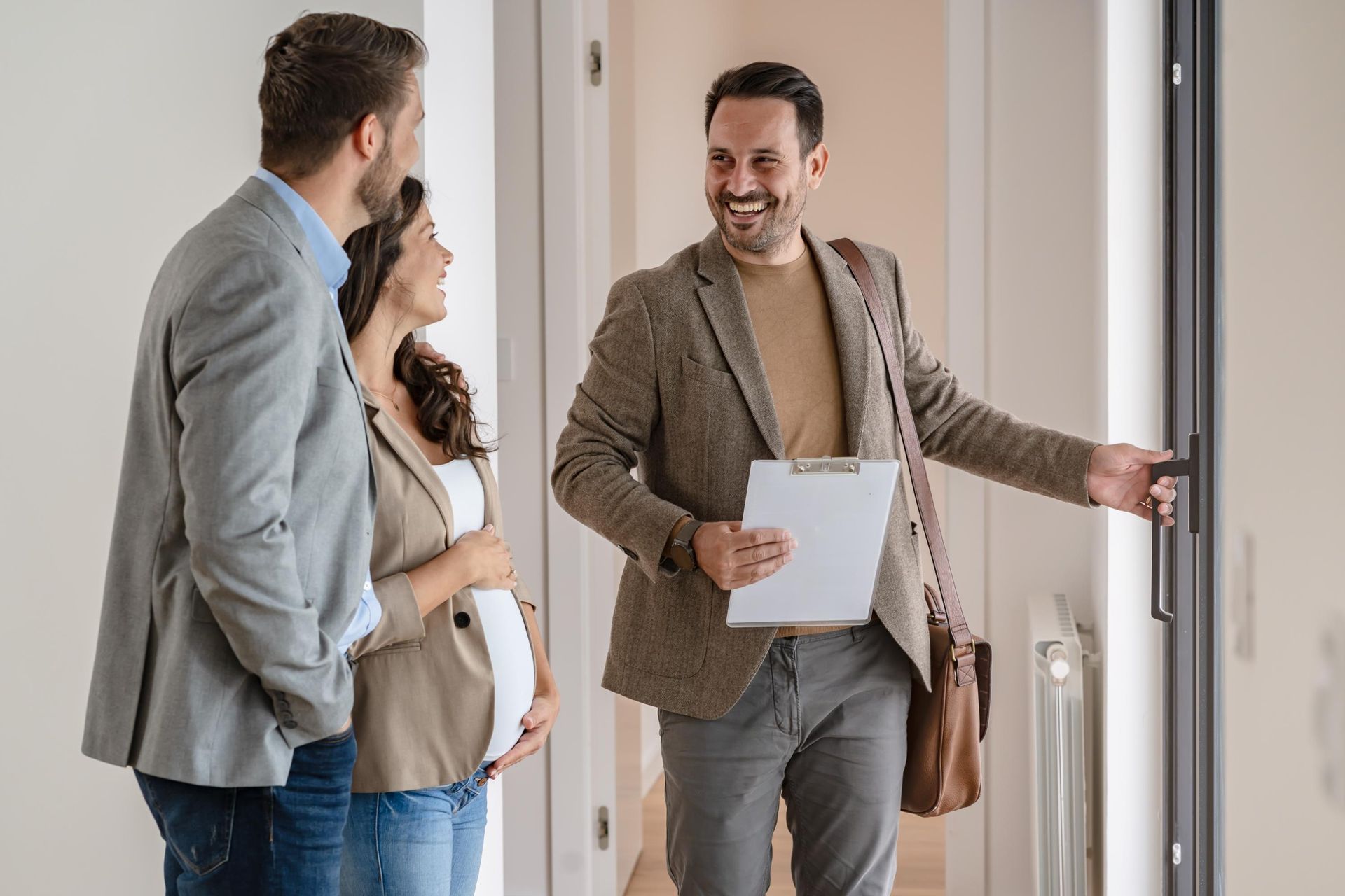 A man is showing a pregnant woman and a man a house.