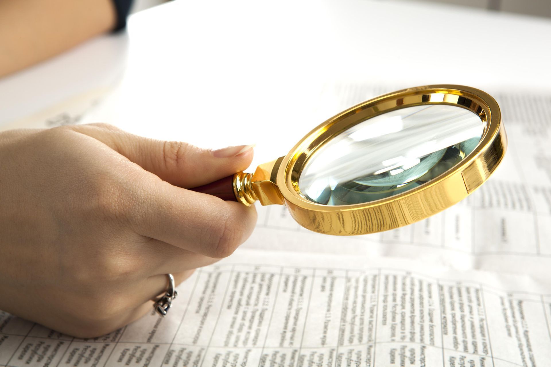 A person is holding a magnifying glass over a piece of paper