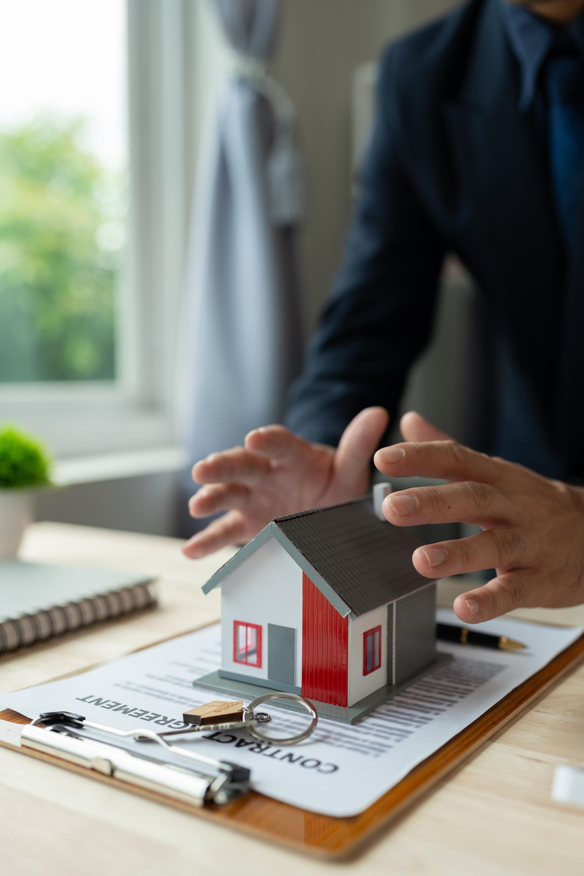 A man is holding a model house on top of a clipboard.