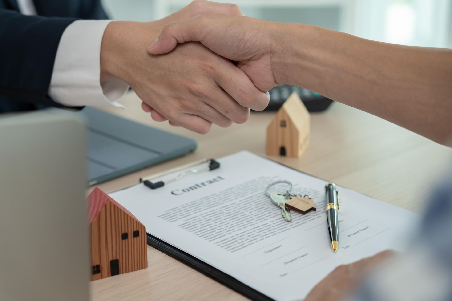 A man and woman are shaking hands over a contract.