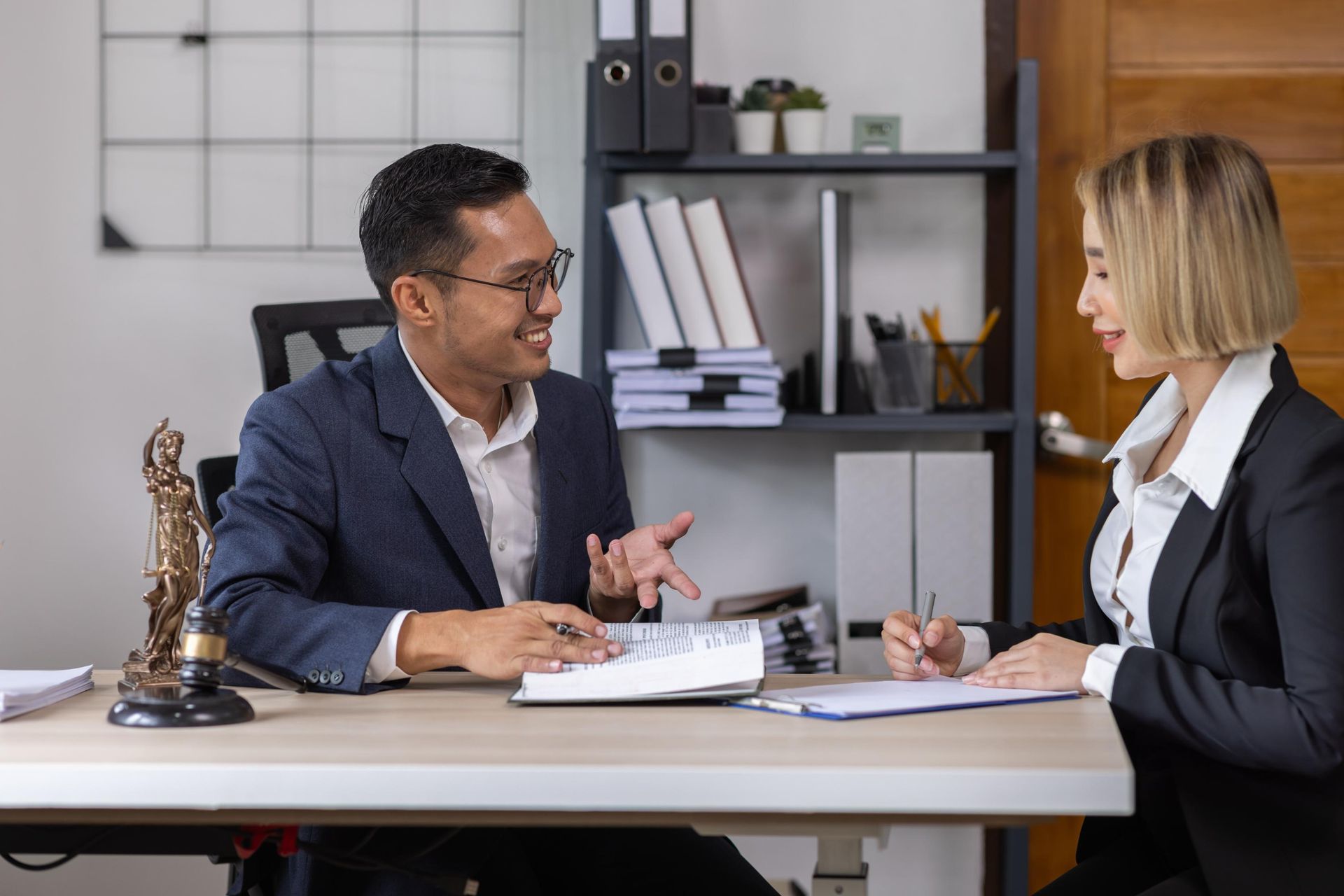 A man and a woman are sitting at a table talking to each other.