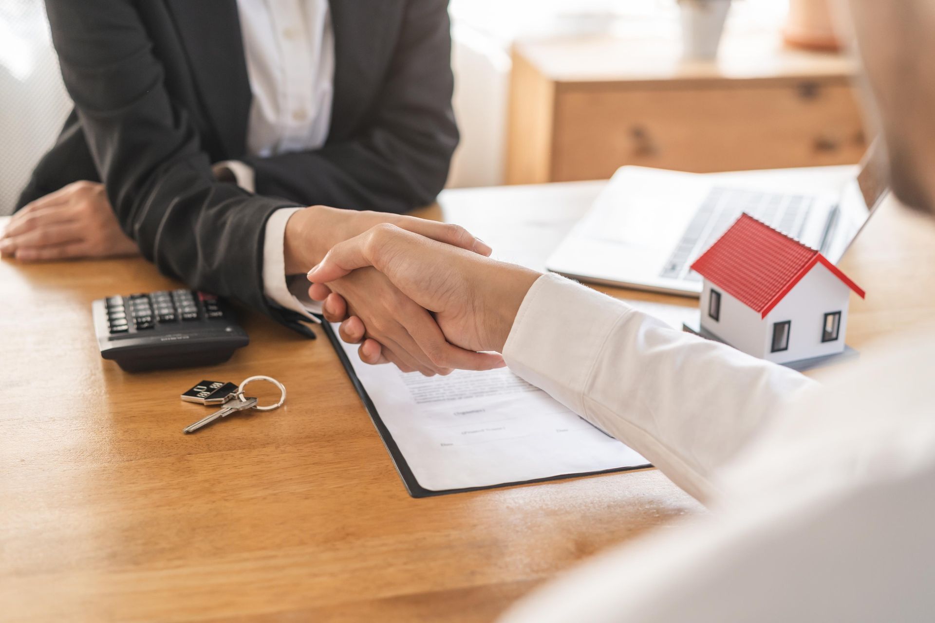 A man and a woman are shaking hands over a table.