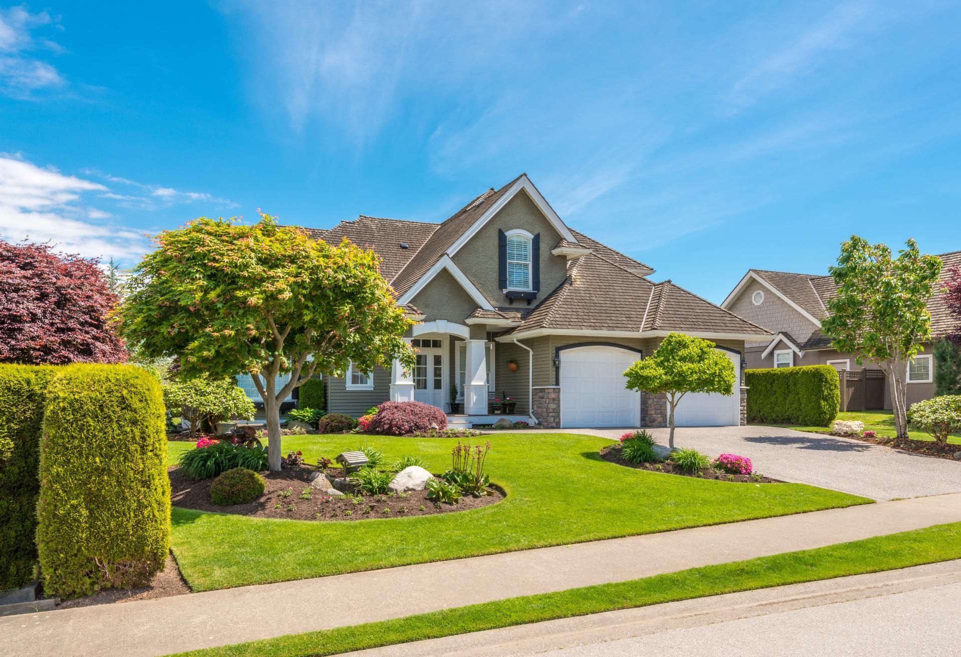 A large house with a lush green lawn and trees in front of it.