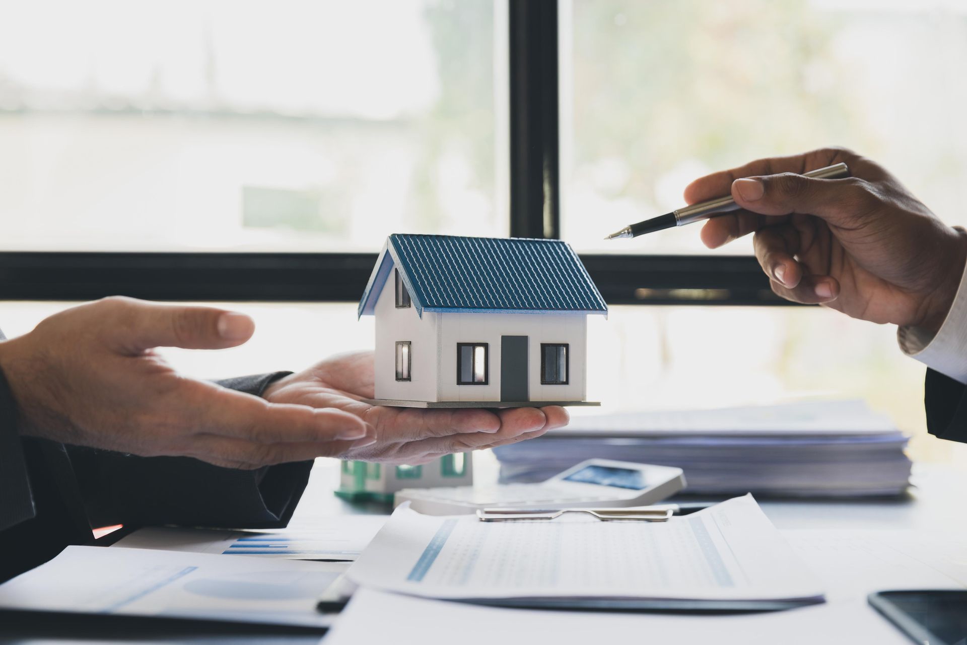 A man is handing a model house to another man.