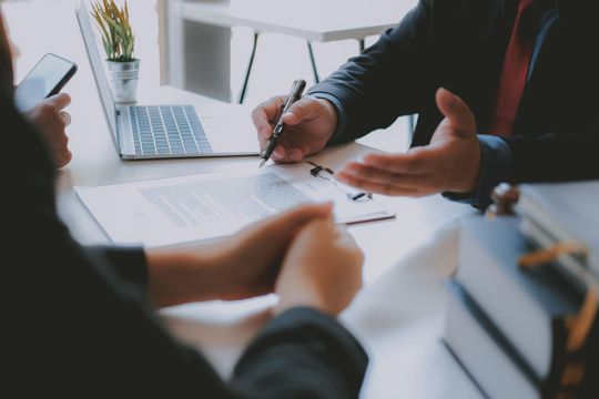 A man and a woman are sitting at a table with a laptop.