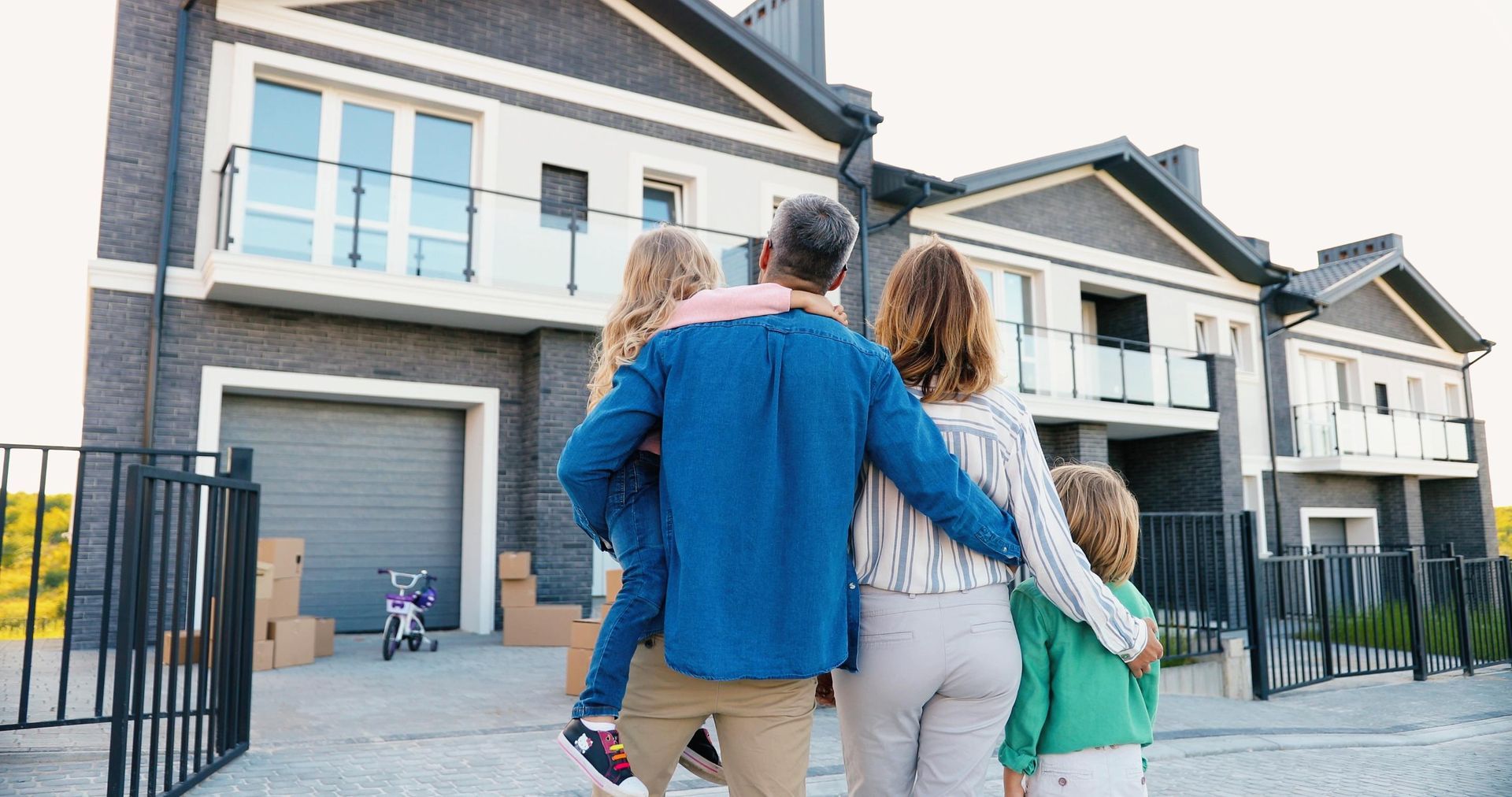 A family is standing in front of a house looking at it.