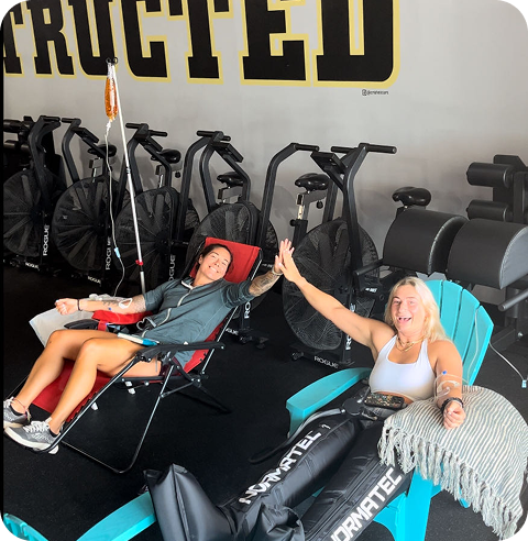 Two women are sitting in chairs in front of a sign that says 