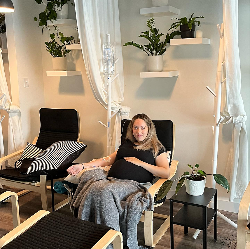 A pregnant woman is sitting in a chair in a living room.
