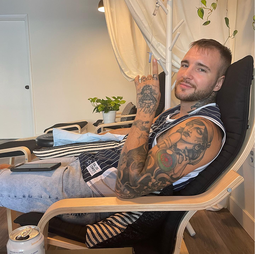 A man with a lot of tattoos is sitting in a chair