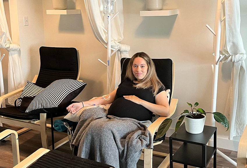 A pregnant woman is sitting in a chair in a room.