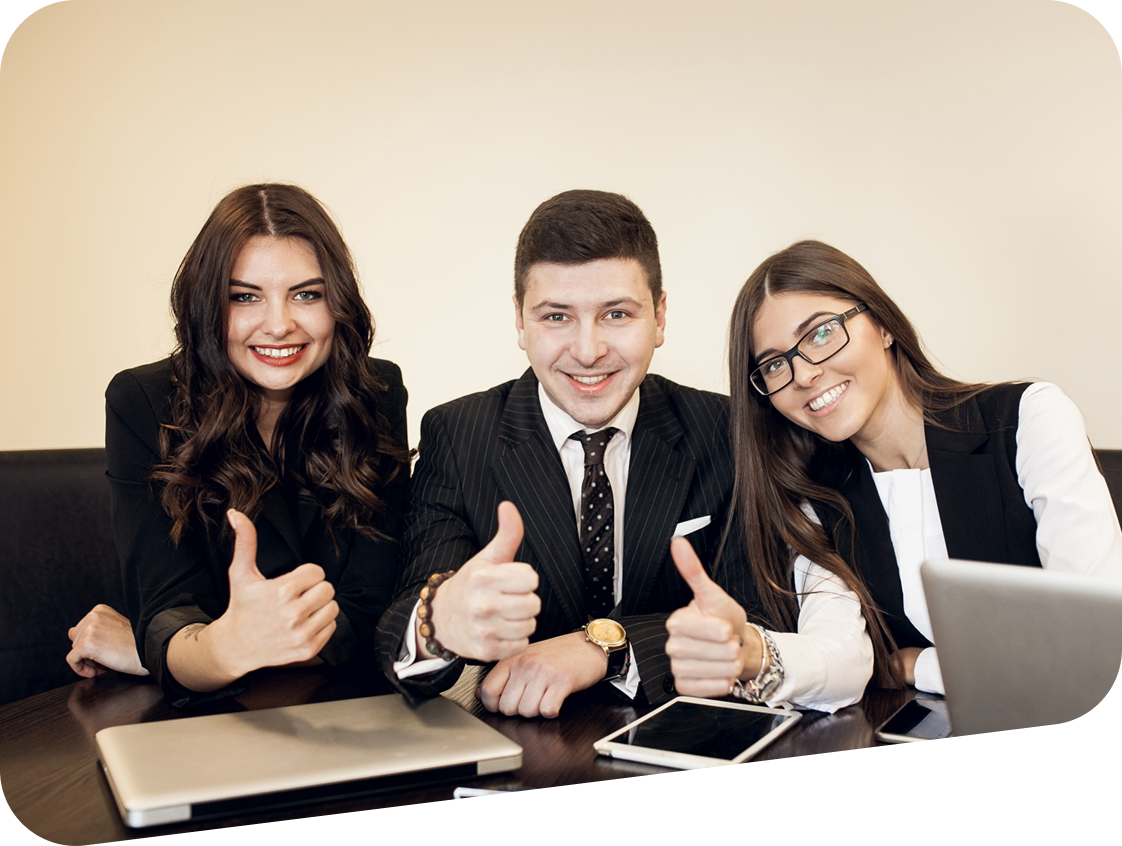 A group of people are sitting at a table giving a thumbs up.