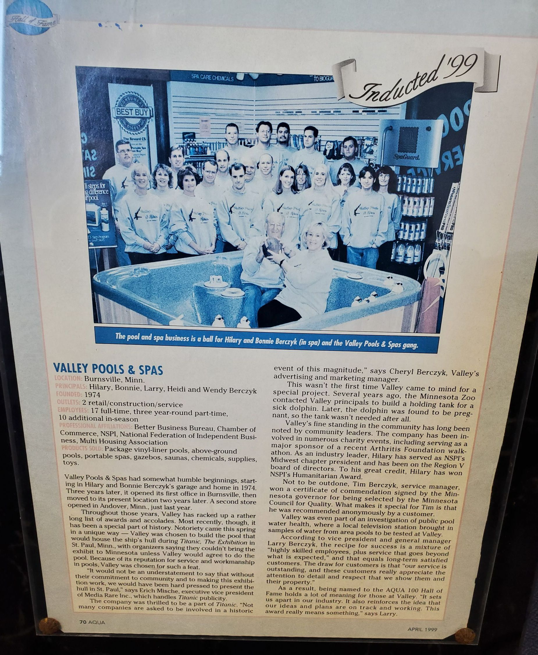 Group photo in a store. People stand around a small pool of water. Text article beneath.