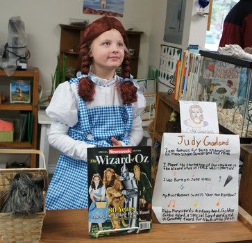 A girl in a wizard of oz costume is holding a book