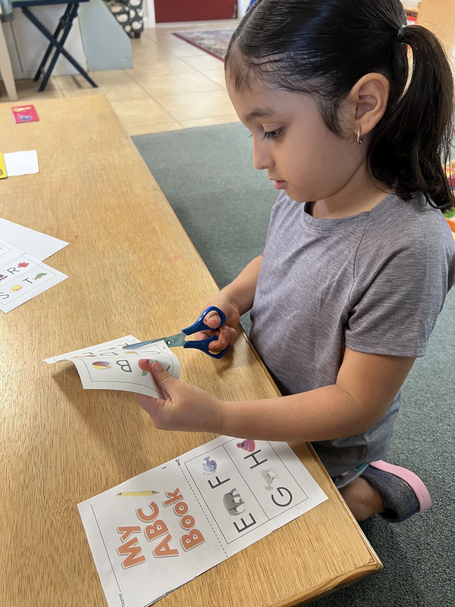 A little girl is cutting a piece of paper with scissors.