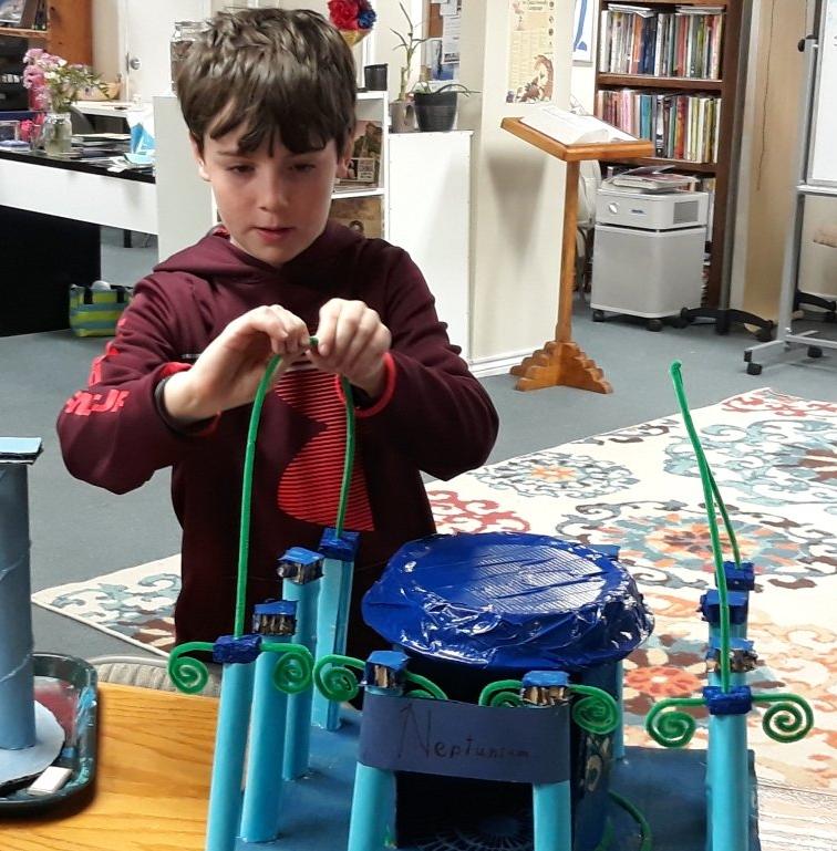 A young boy is playing with a model of a castle