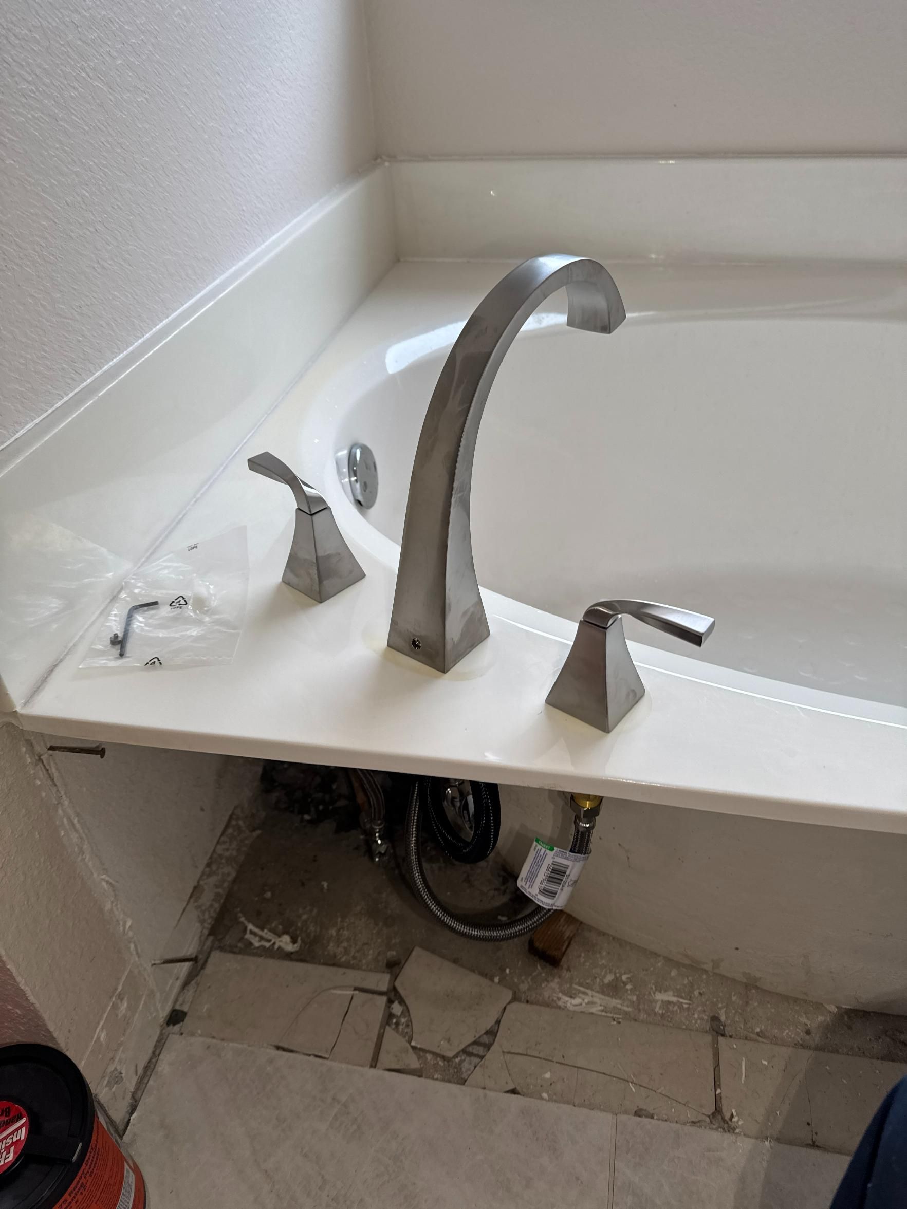 Tub faucet with two handles and a curved spout, in a white tub deck.