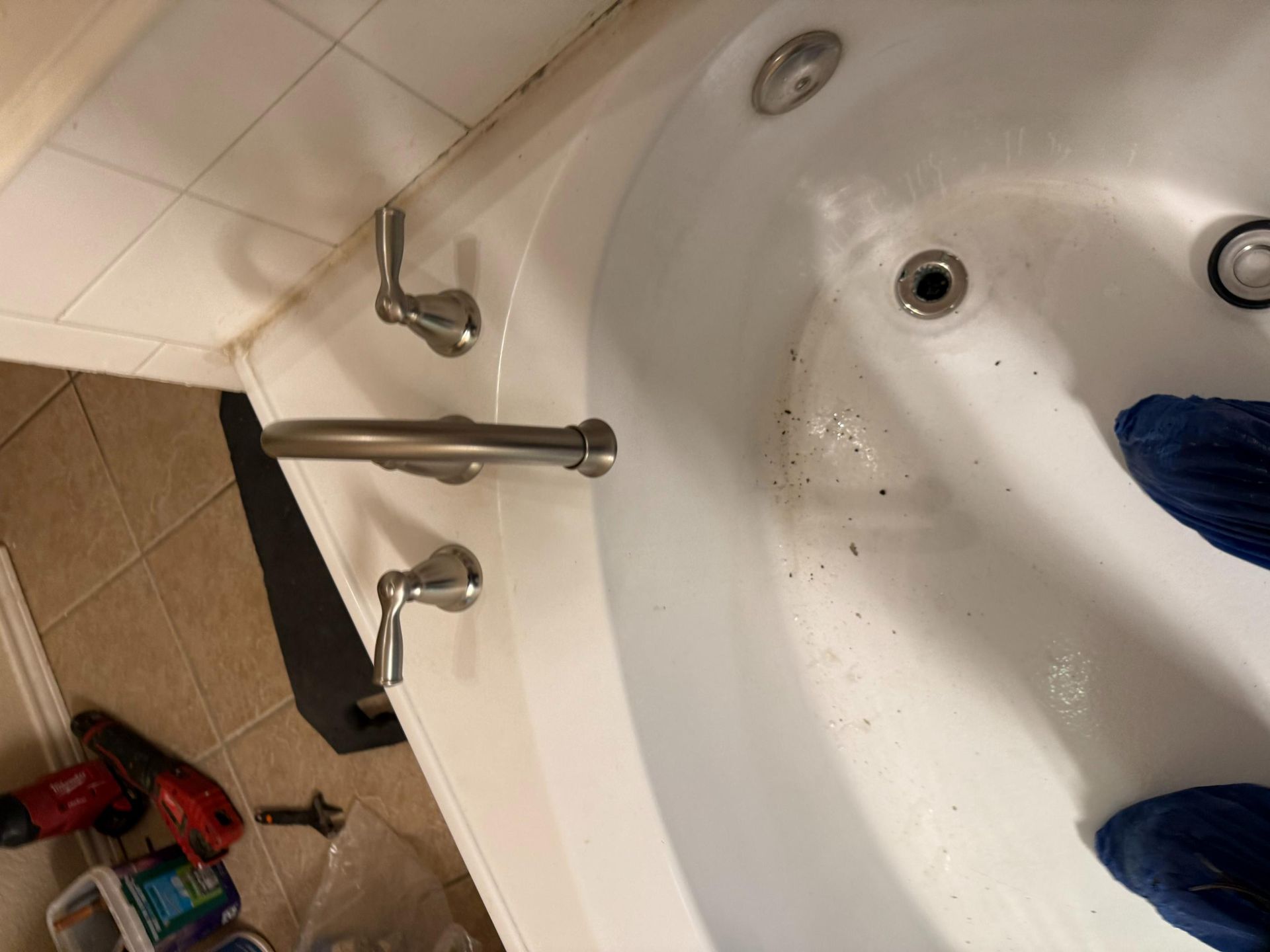 White bathtub with faucet, jets, and handle against tiled wall.