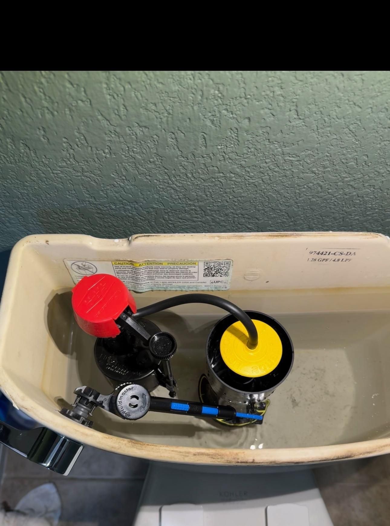 Toilet tank interior with a red and black fill valve and a yellow flapper.