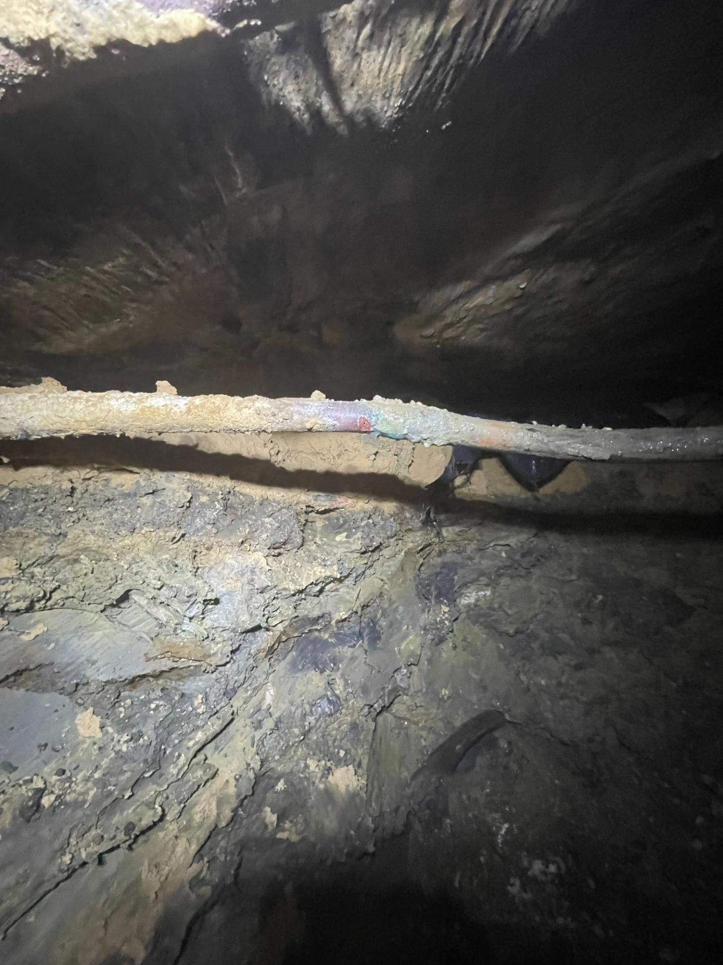 Inside of a cave. Rough, dark rock surfaces. Horizontal beam spans the opening.