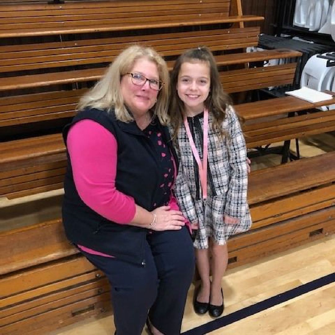 A woman and a girl are sitting on a bench in a gym.