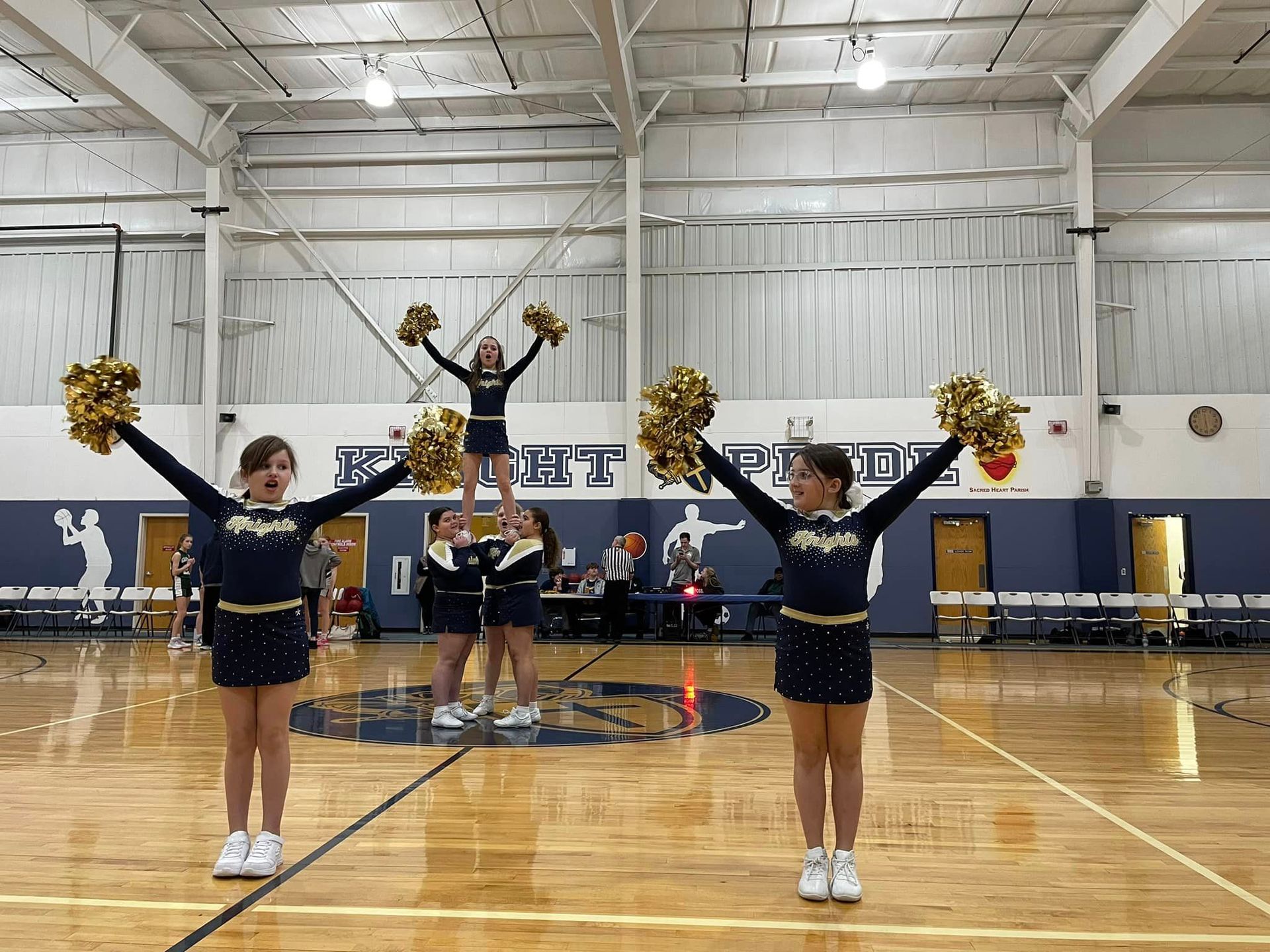 A group of cheerleaders are performing on a basketball court