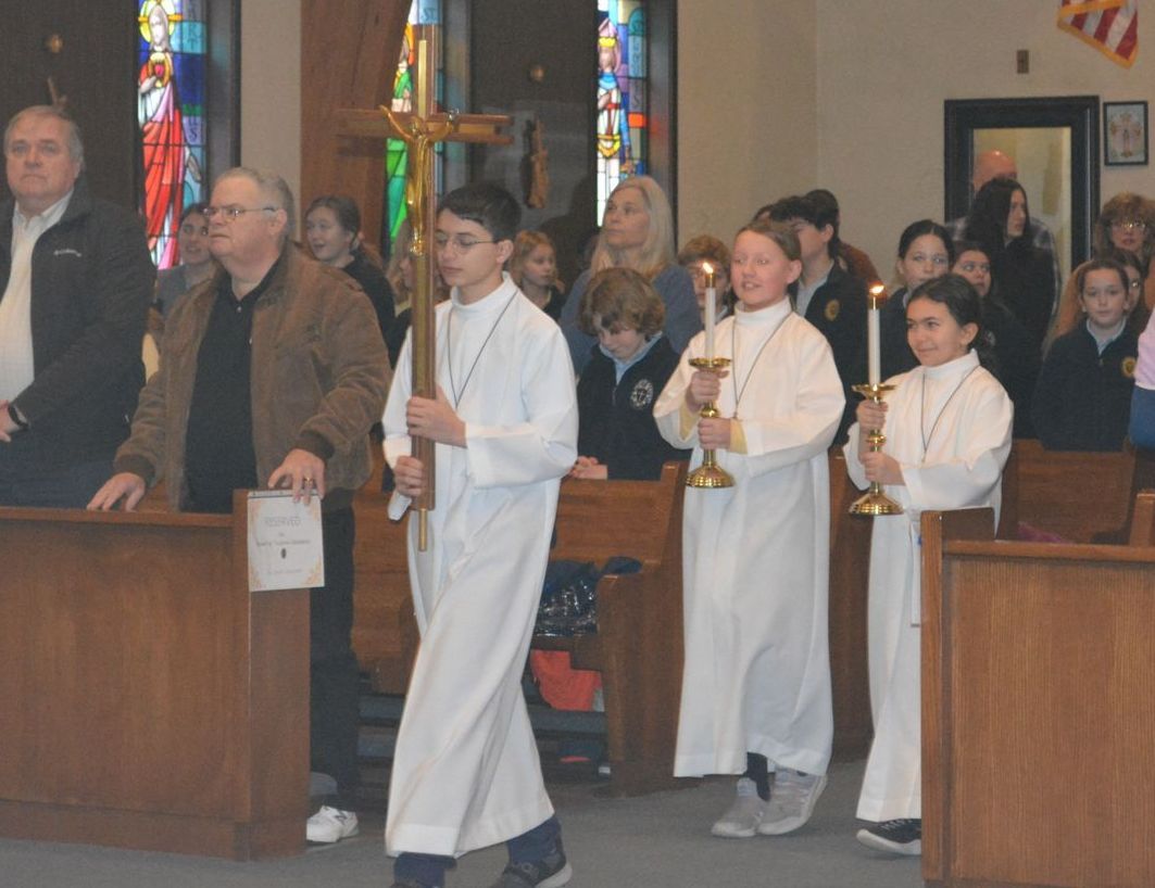 A group of people holding candles and a cross in a church